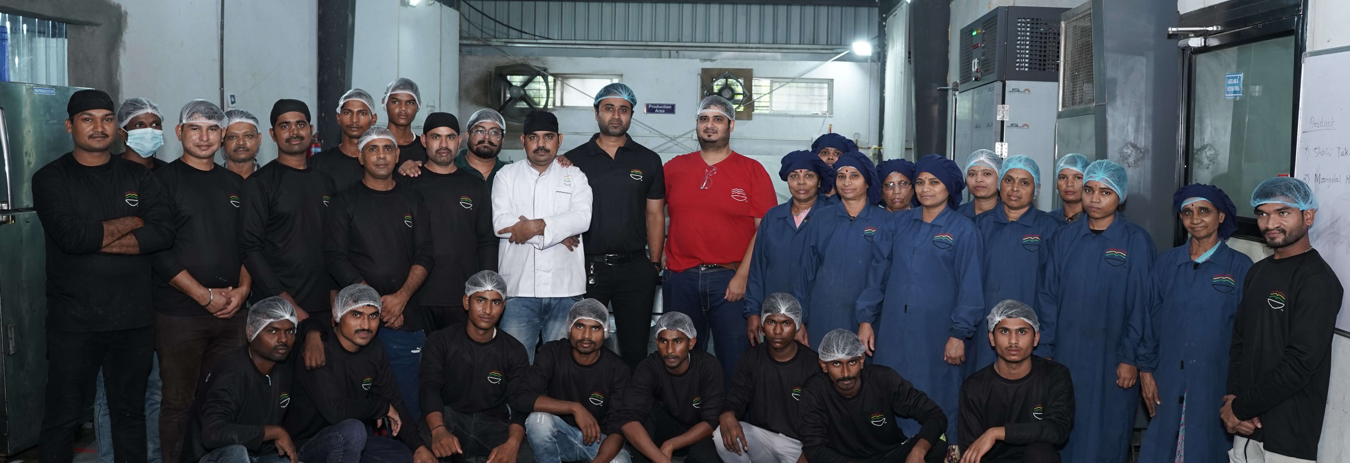 Complete Scandalous Foods production team in professional uniforms at their state-of-the-art facility